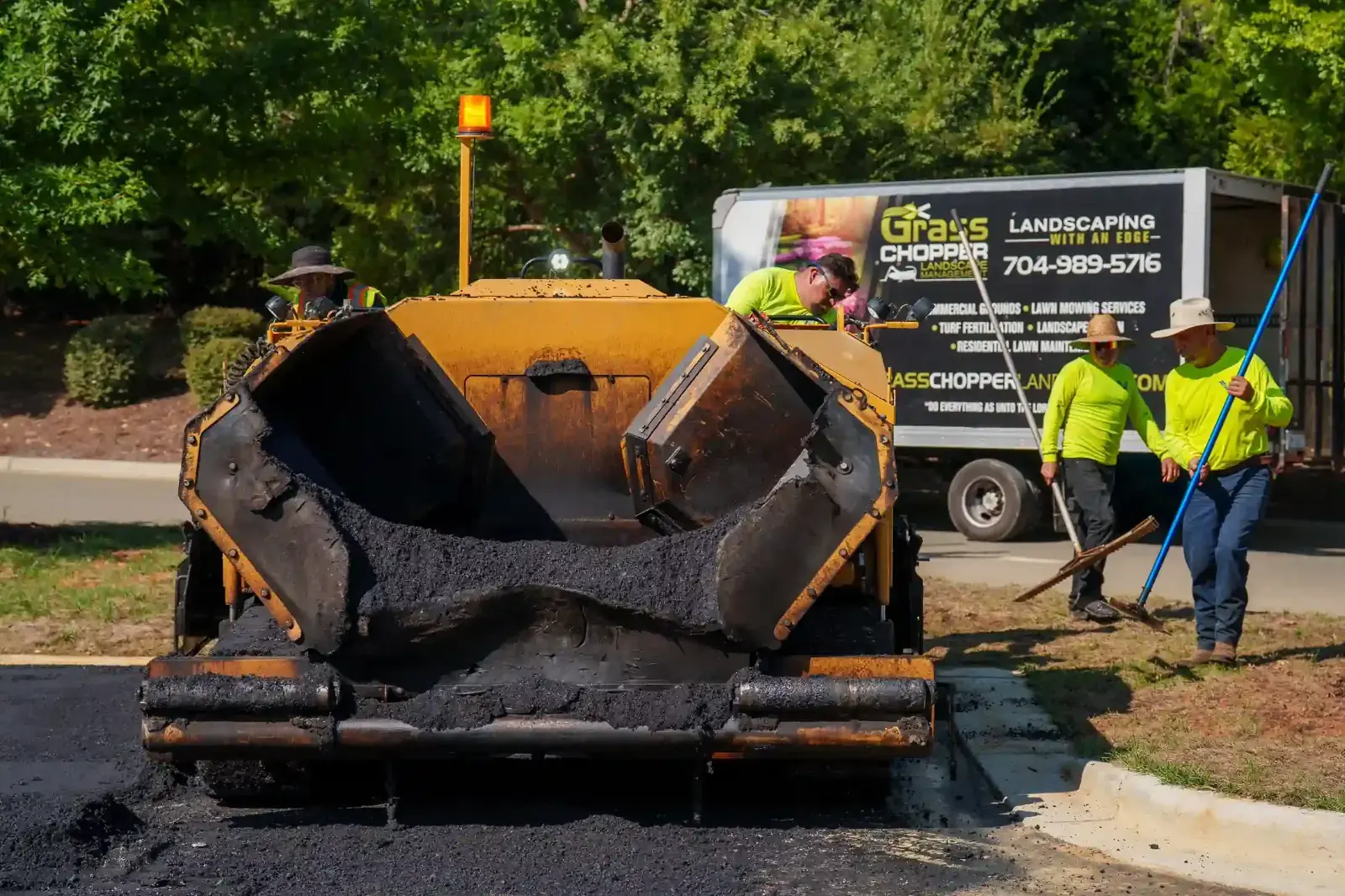 Crew loading the asphalt paver hopper during a parking lot reconstruction