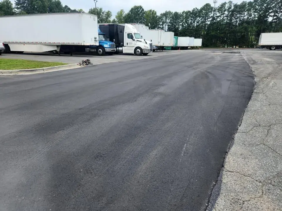 Heavy duty asphalt truck lot with tractor trailers at an industrial facility