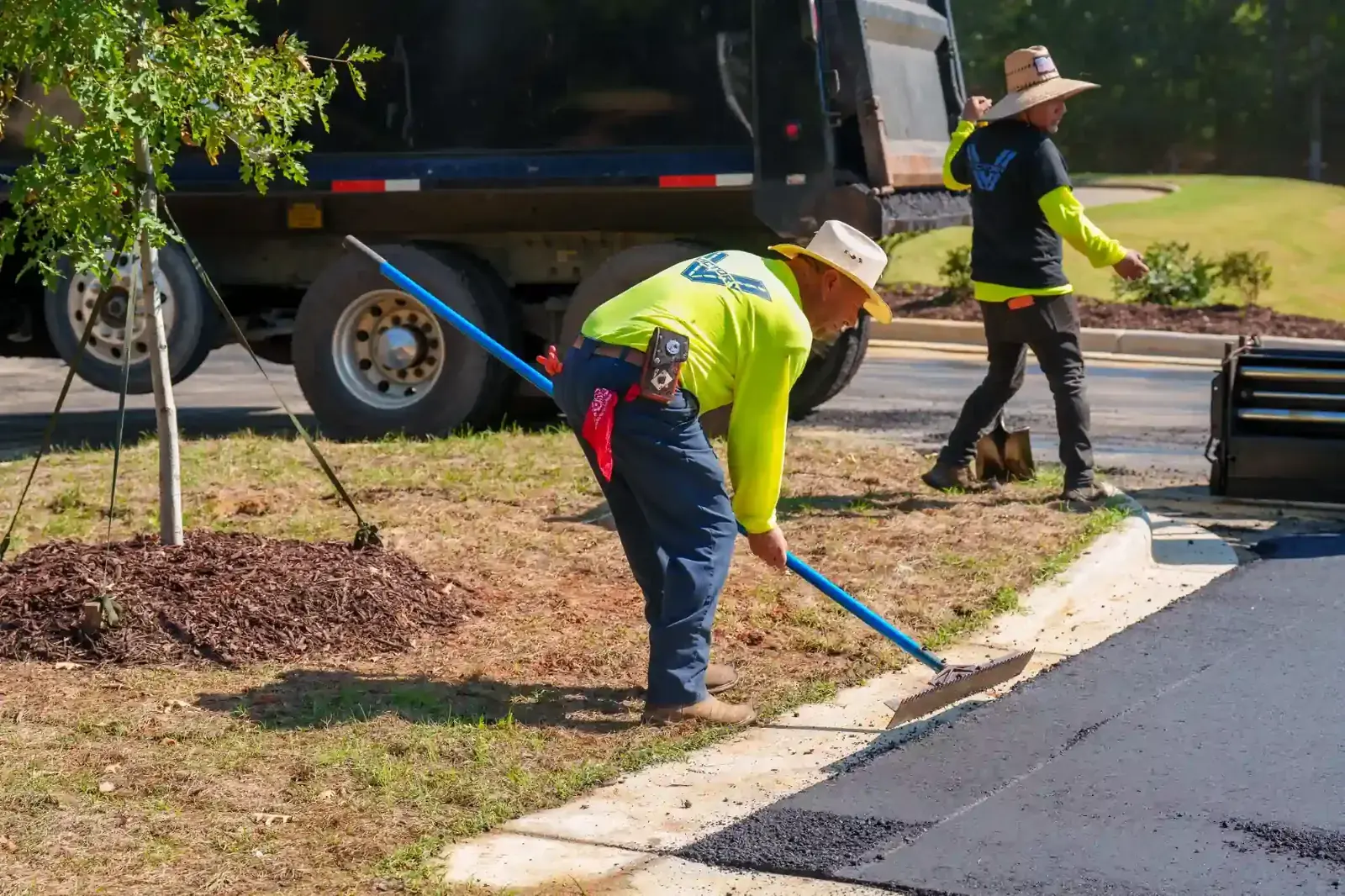Crew raking the edge of a new asphalt section