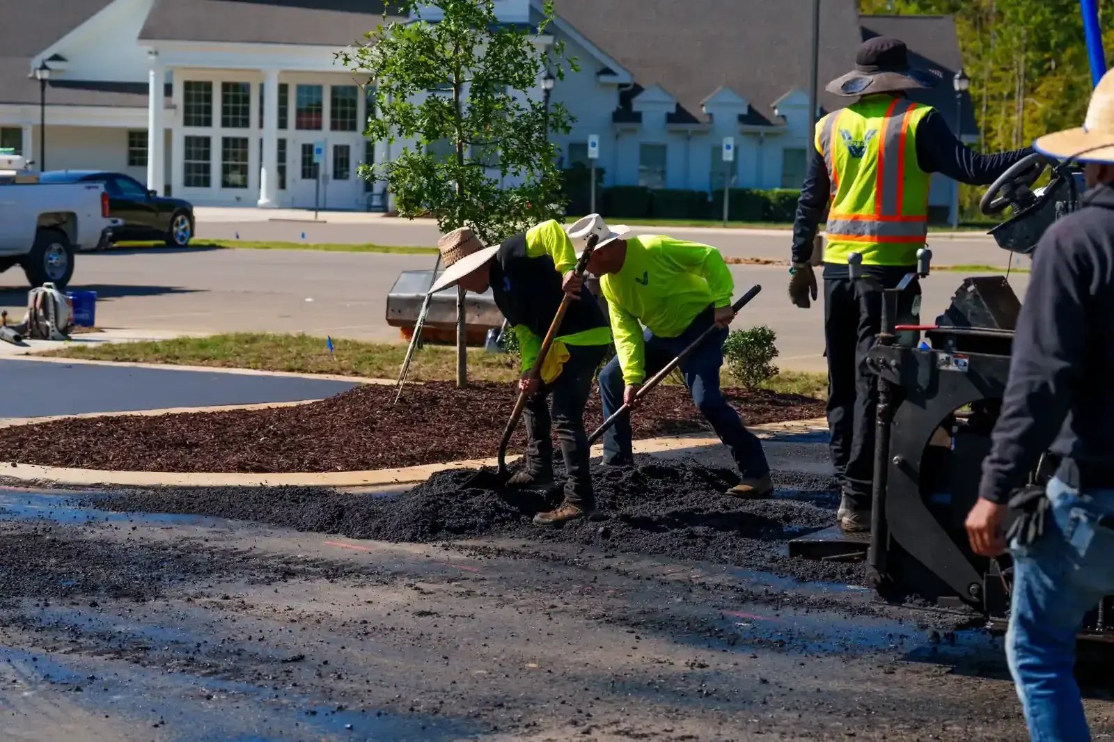 Crew raking hot asphalt into a full depth parking lot repair