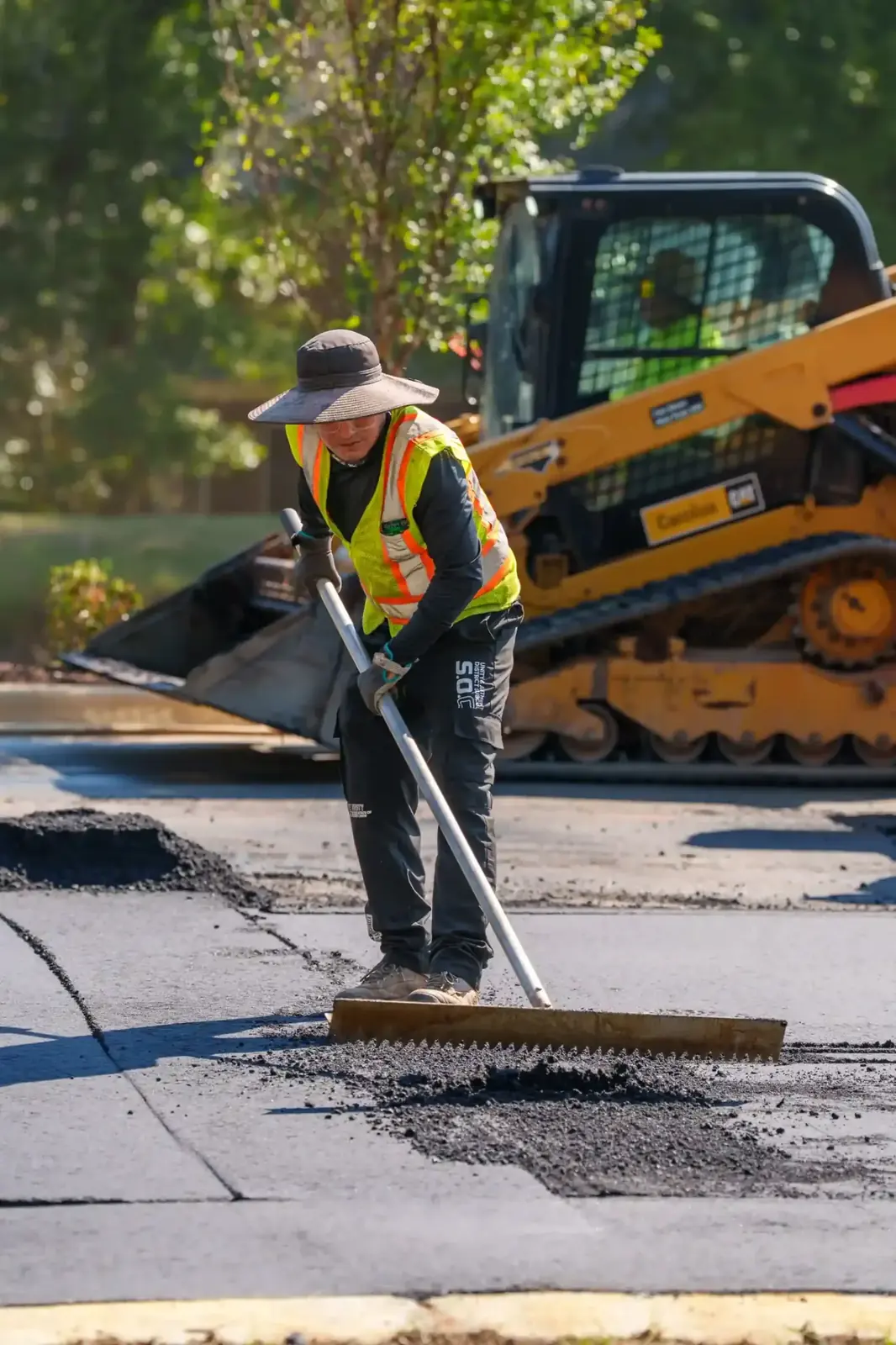 Crew spreading asphalt with a skid steer
