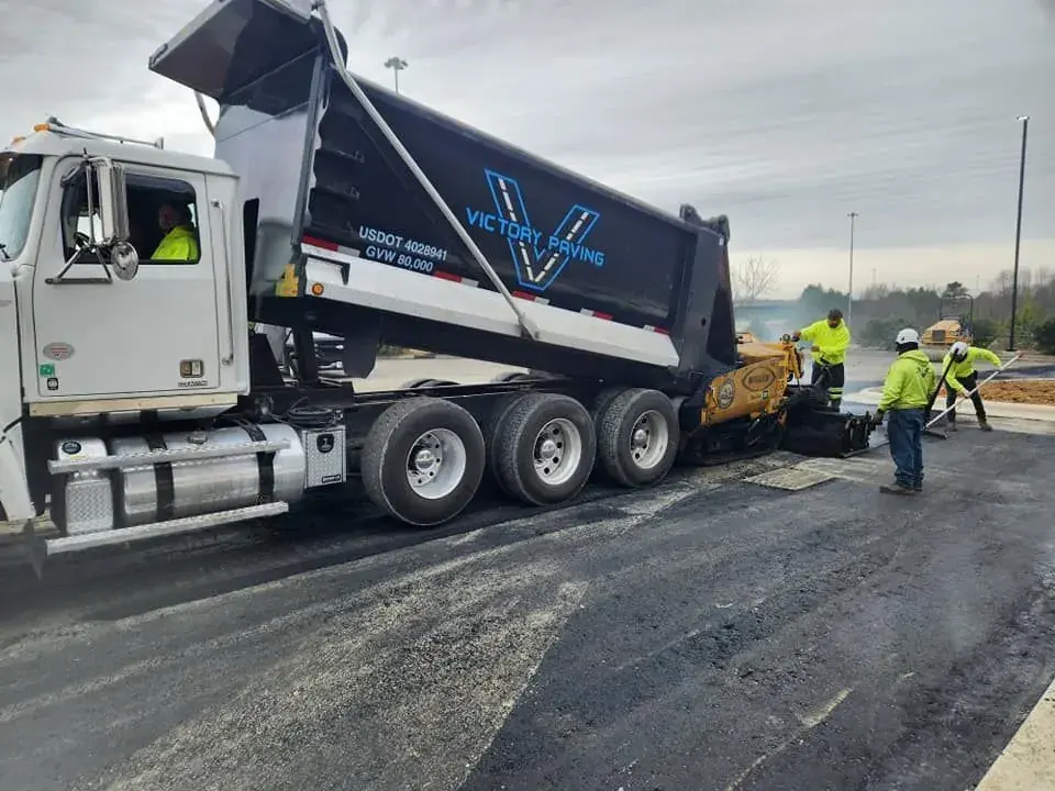 Victory Paving dump truck feeding an asphalt paver on a North Carolina commercial paving job